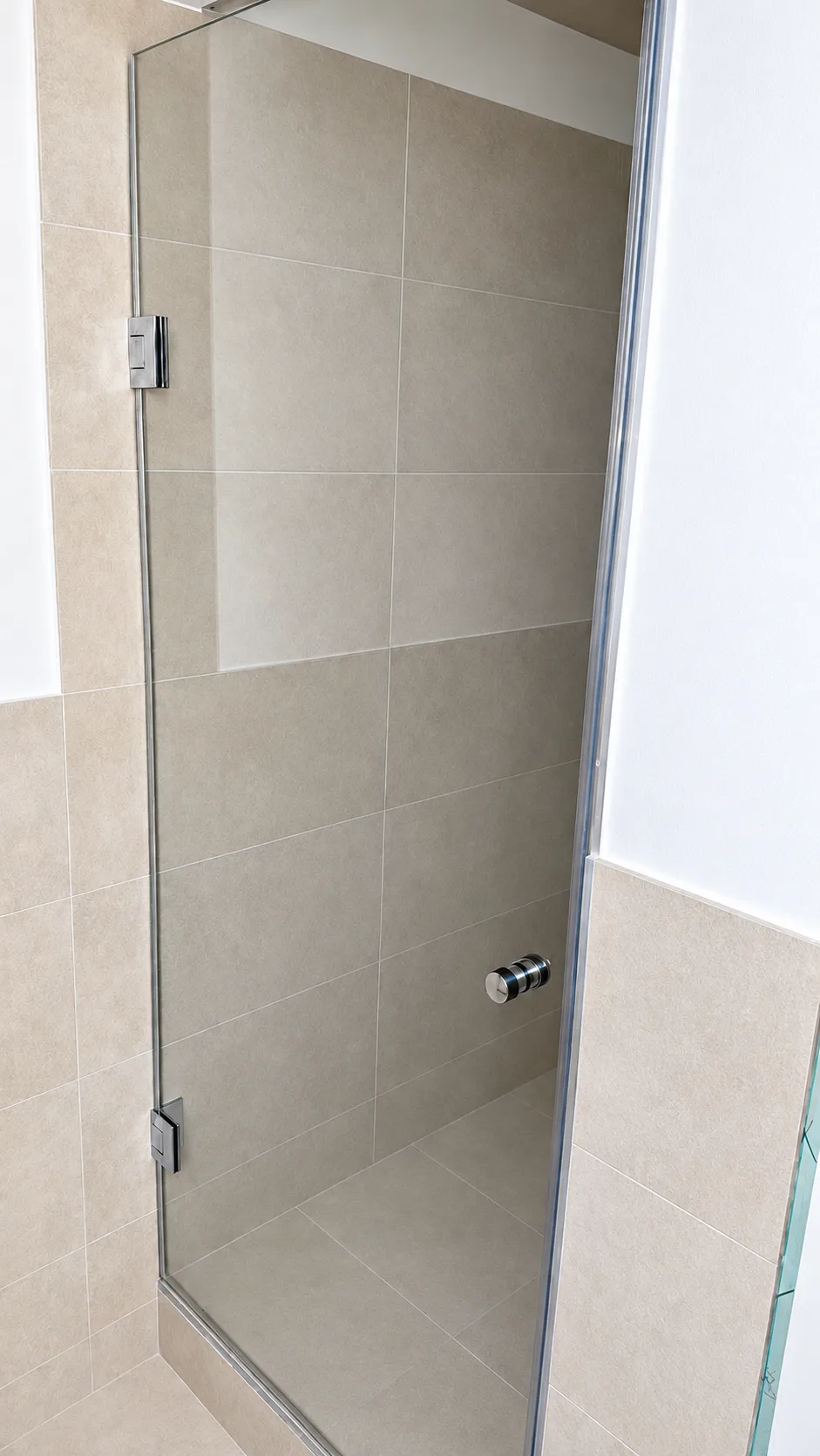 Nischendusche mit einzelner Glastür in einer beige gefliesten Nische